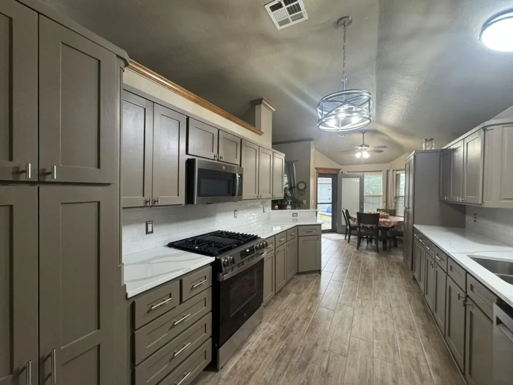 Galley-style kitchen with grey cabinets, white countertops, and stainless steel appliances.